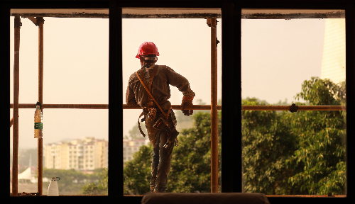 脚手架上眺望城市的年轻建筑工人.jpg